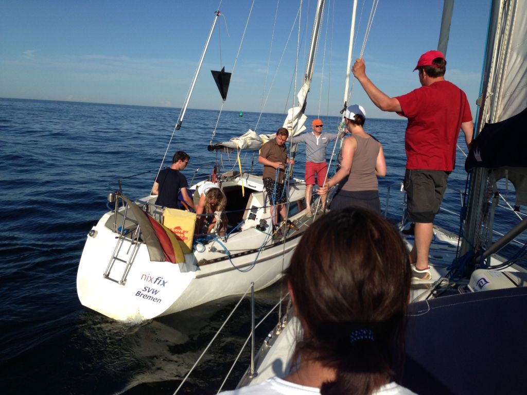Mehrere Personen segeln auf einer Yacht während eines SKS-Praxistörns auf See. Die Crew führt Segelmanöver durch und sammelt Seemeilen im Rahmen von Meilen- und Prüfungstörns für den Sportküstenschifferschein.