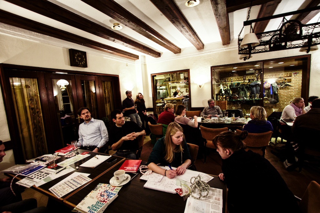 Teilnehmende eines SBF-Binnen- und SBF-See-Theoriekurses sitzen an Tischen in einem Schulungsraum und bearbeiten gemeinsam Lernunterlagen und Seekarten. Die Szene zeigt konzentriertes Lernen in kleiner Gruppe während der theoretischen Ausbildung zum Sportbootführerschein.